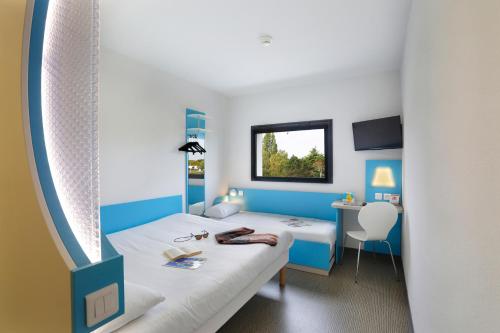 a blue and white room with a bed and a desk at First Inn Hotel Blois in Blois