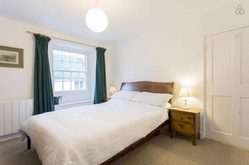 a bedroom with a bed with green curtains and a window at Fisherman's Cottage in Saint Mawes