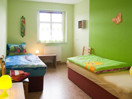 a green room with two beds and a table at Ferienwohnung Knoth in Altenburg