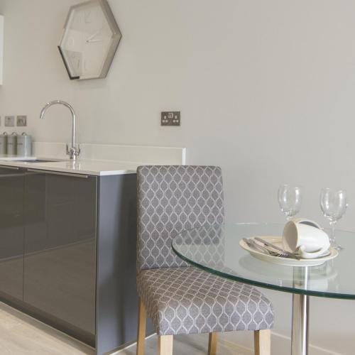 a kitchen with a glass table and a chair at Citystay Living - Vesta Apartments in Cambridge