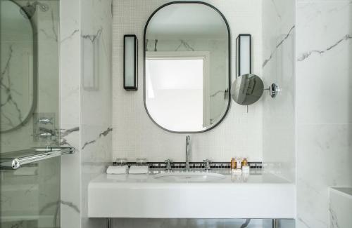 a white bathroom with a sink and a mirror at Hôtel La Tamise - Esprit de France in Paris