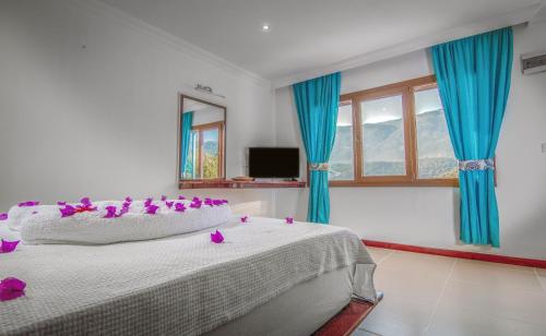 ein Schlafzimmer mit einem Bett mit lila Blumen darauf in der Unterkunft Korsanada Hotel in Kaş