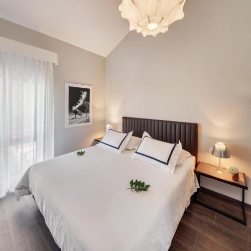 a bedroom with a large white bed with a chandelier at Hotel Milna Osam - Adults Only in Milna
