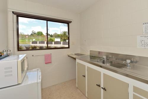 eine Küche mit einem Waschbecken und einem Fenster in der Unterkunft Waterfalls Estate - Falls Motel & Waterfront Campground in Paihia