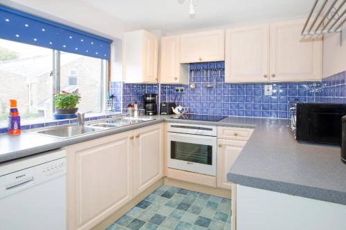 a kitchen with white cabinets and blue tiles at Bright Oxford Apartment in Oxford