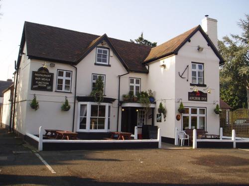 a white building with benches in front of it at Anchor Inn Fladbury in Fladbury
