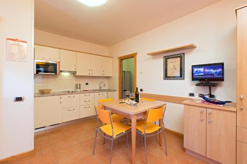 cocina con mesa de madera y sillas amarillas en Art Apartments Casa Napell, en Livigno