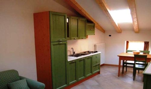 a green kitchen with a sink and a table at Residence Centrale in Dro