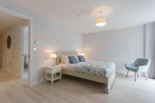 a white bedroom with a bed and a chair at Citystay - Vesta Apartments in Cambridge