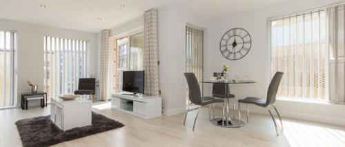 a living room with a table and chairs and a clock at Citystay Living - Vesta Apartments in Cambridge