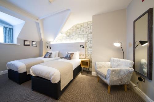 a hotel room with two beds and a chair at The Cow & Calf by Innkeeper's Collection in Ilkley
