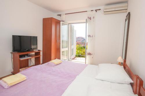 a bedroom with a bed and a tv and a window at Apartments Beslema in Dubrovnik