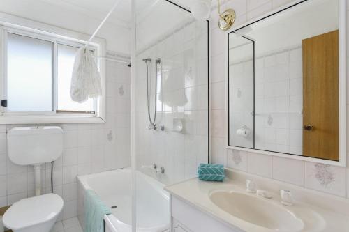 a white bathroom with a sink and a toilet at Tyrone Beach House in Rye