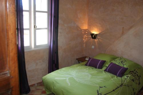 a bedroom with a green bed and a window at La Maison derrière la Fontaine in Buis-les-Baronnies