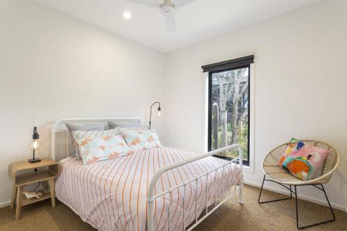 a white bedroom with a bed and a chair at Yaringa St Andrews in Saint Andrews Beach