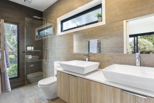 a bathroom with two sinks and a toilet and a window at Yaringa St Andrews in Saint Andrews Beach