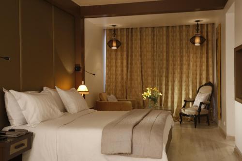 a bedroom with a large white bed and a chair at Hotel Villa Didon Carthage in Carthage