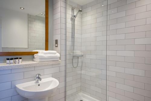 a white bathroom with a sink and a shower at The Cow & Calf by Innkeeper's Collection in Ilkley