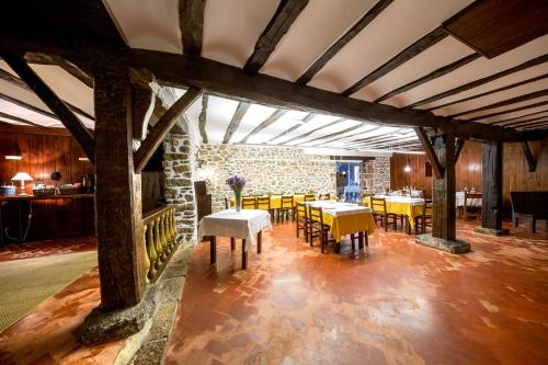 a dining room with tables and chairs and a stone wall at Goiko-Benta Ostatua in Oñati