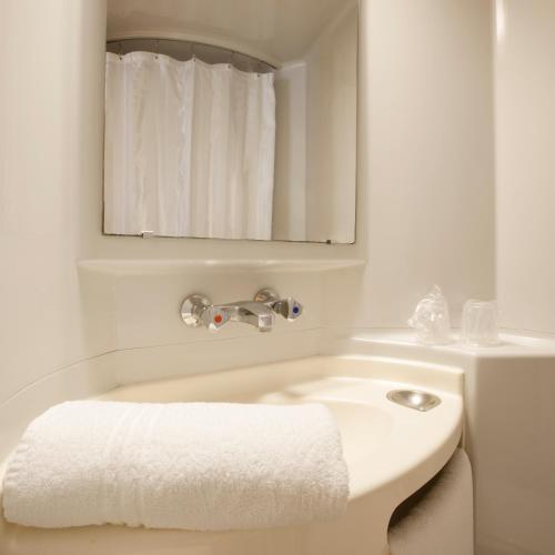 Un baño blanco con lavabo y espejo. en Premiere Classe Compiegne - Jaux, en Jaux