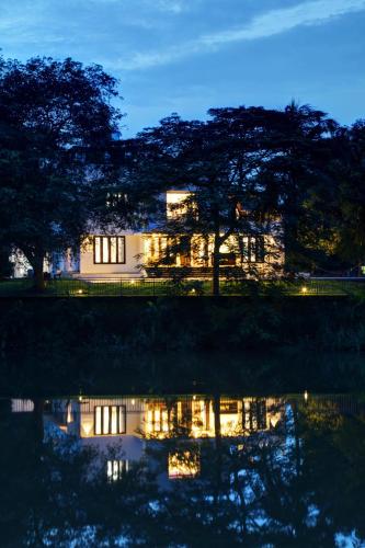 a house lit up at night with its reflection in the water at Nadhiyoram River Retreat in Cochin