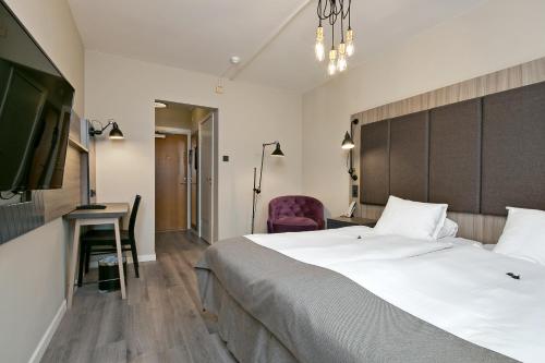 a hotel room with a bed and a desk and a tv at First Hotel Brommaplan in Stockholm