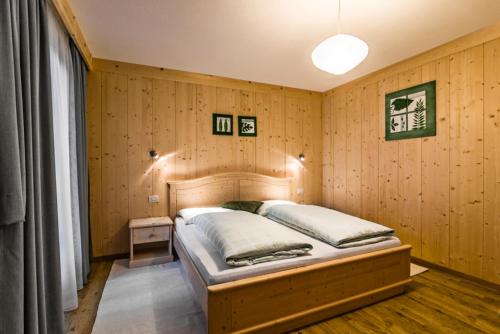 ein Schlafzimmer mit einem Bett in einer Holzwand in der Unterkunft Ciasa Confolia in Kurfar
