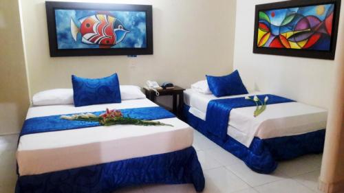 2 Betten mit blauer und weißer Bettwäsche in einem Zimmer in der Unterkunft Hotel Tumburagua Inn Ltda in Neiva