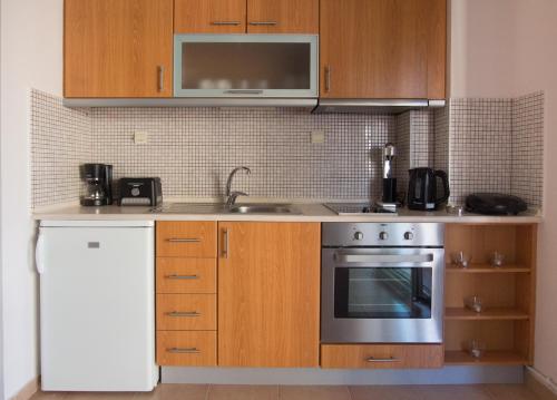 a kitchen with wooden cabinets and a stove top oven at Giorgio Deluxe Apartments in Kavala