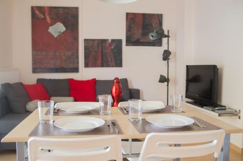 a dining room table with white plates and a tv at Giorgio Deluxe Apartments in Kavala