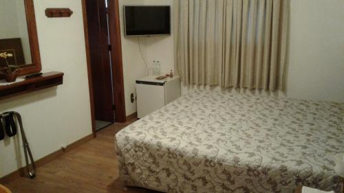 a small bedroom with a bed and a television at Hotel San Carlos in Carlos Barbosa