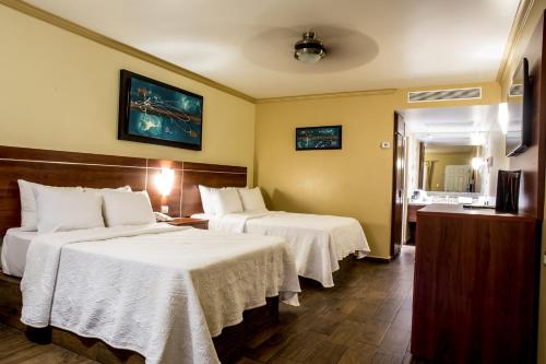 Habitación de hotel con 2 camas con sábanas blancas en Hotel San Sebastian, en Hermosillo