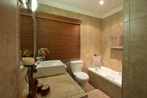 La salle de bains est pourvue de toilettes, d'une baignoire et d'un lavabo. dans l'établissement Pin Oak Cottage, à Vryheid