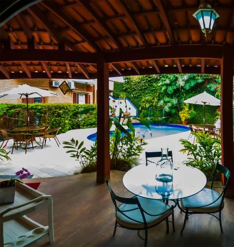 a patio with a table and chairs and a pool at Hotel Villa Di Rimini in Ubatuba