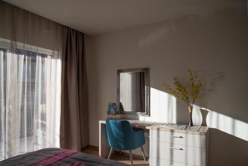 a bedroom with a desk and a blue chair and a window at Apartment Cristian 2 in Timişoara