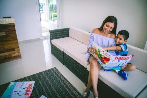 a woman and child sitting on a couch reading a book at Luxury Hotel Inn in Peñita de Jaltemba