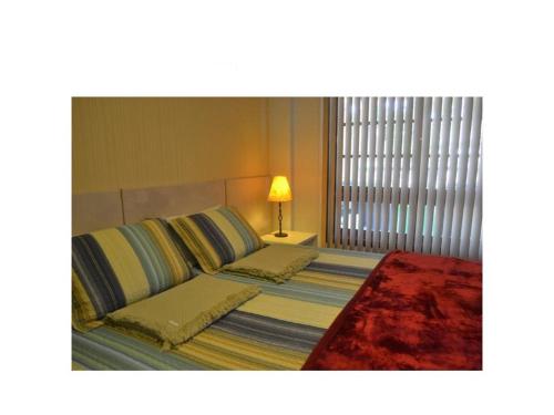 Un dormitorio con una cama y una lámpara sobre una mesa. en Kauai Praia do Forte, en Praia do Forte
