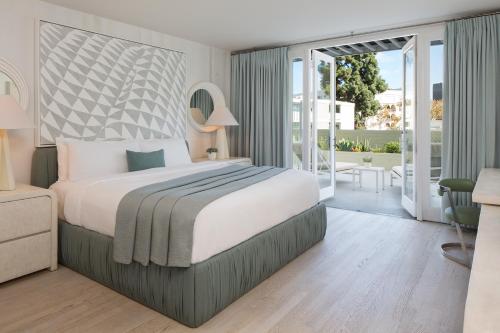 a bedroom with a large bed and a balcony at Avalon Hotel Beverly Hills, a Member of Design Hotels in Los Angeles