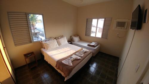 a small bedroom with two beds and two windows at Pousada Maré Enseada in Guarujá