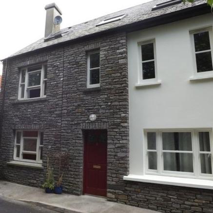 a brick house with a red door and windows at Modern Home in the Heart of Rosscarbery Village in Rosscarbery