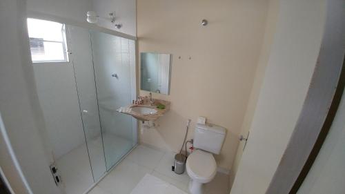 a bathroom with a shower and a toilet and a sink at Pousada Maré Enseada in Guarujá