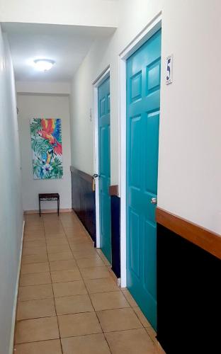 a hallway with two blue doors and a tile floor at Cerrito Tropical Eco Lodge in Taboga