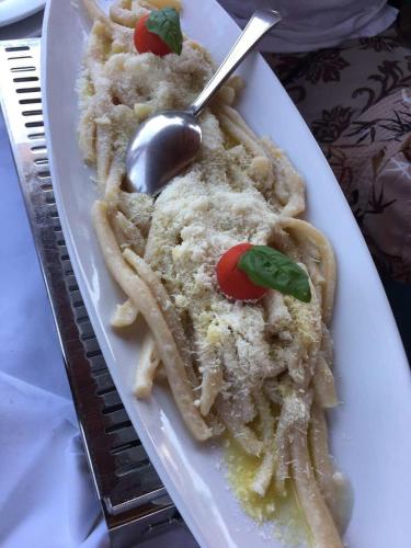 a white plate of food with pasta and a spoon at Apartments Stermasi in Saplunara