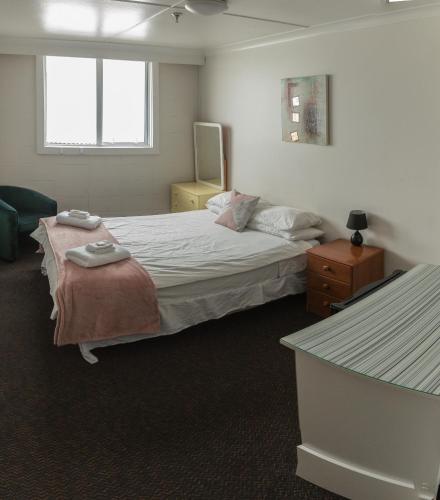 a bedroom with a large bed and a table at Downtown Backpackers & Accommodation in Nelson