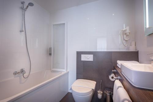 a bathroom with a tub and a toilet and a sink at Joy Hotel in Amsterdam