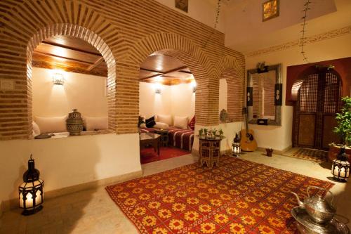 una sala de estar con sofá y una habitación con alfombra en Riad Hna Ben Saleh, en Marrakech