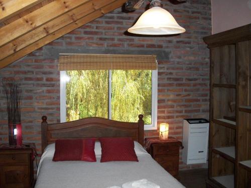 a bedroom with a bed with red pillows and a window at Cabañas Ananda in Villa Ventana