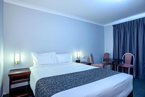 a hotel room with a bed and chairs at Bushman's Motor Inn in Lithgow