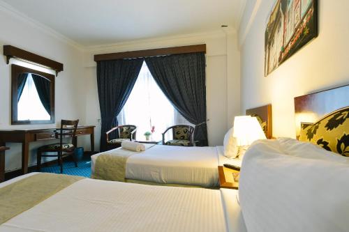 a hotel room with two beds and a desk at Hotel Seri Malaysia Melaka in Melaka