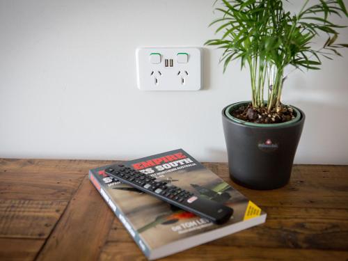 a remote control sitting on a book next to a potted plant at SkyLodge Temora in Temora